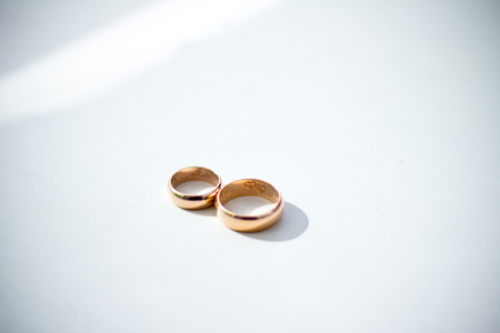 Gold wedding rings on white surfaceの写真素材