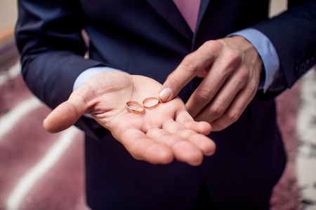 Gold wedding rings on groom's palmの写真素材