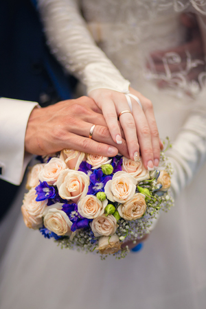 Hands of groom and bride on a blue wedding bouquetの写真素材