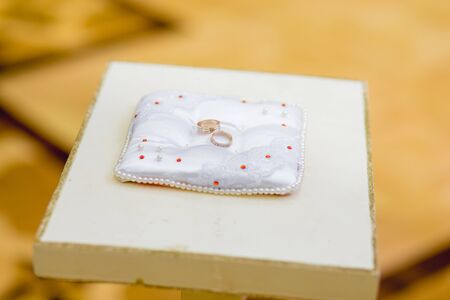 Gold wedding rings on a white pillowの写真素材