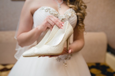 Bride holding beautiful white wedding shoesの写真素材