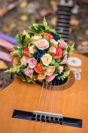 Wedding bouquet of colorful flowers lying on the guitar