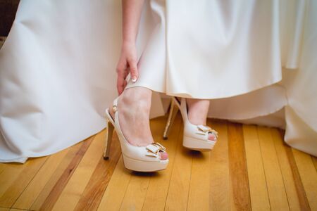 Bride holding beautiful beige wedding shoesの写真素材