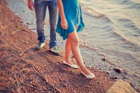 A loving couple walks on the deserted beach at sunsetの写真素材