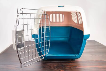 Plastic cage carrying for dogs and cats on a wooden table. Travel transportation, veterinary clinic and pet care conceptの写真素材