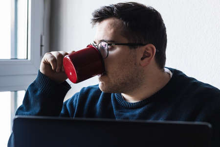 A man is working at home and drinking a coffee.の写真素材