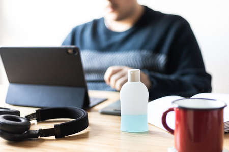 A man is working at home and using a hand sanitizer, a solution against the spread of corona virus for quarantined employeesの写真素材