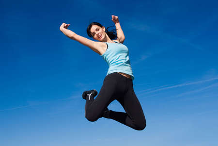 Attractive happy young woman jumping - sky background 