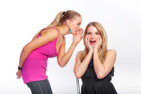 A young girl whispers a secret into her friends earの写真素材