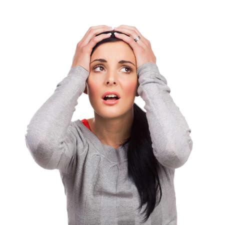 Portrait of unhappy young woman holding hands in head - isolated on white background の写真素材