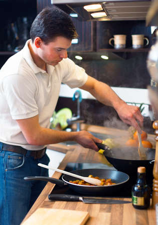 Young handsome man preparing lunch in kitchen の写真素材