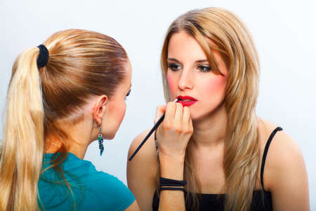 Make-up artist applying lipstick with a brush on model's lipsの写真素材