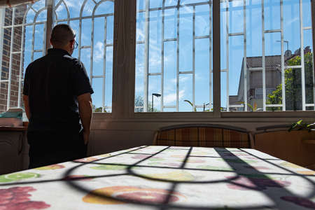 man watching through the window with bars to get to safety from the pandemicの写真素材