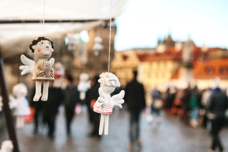 Statues Souvenirs in the form of an angel hanging on the background of Prague. a blurry crowd of peopleの写真素材