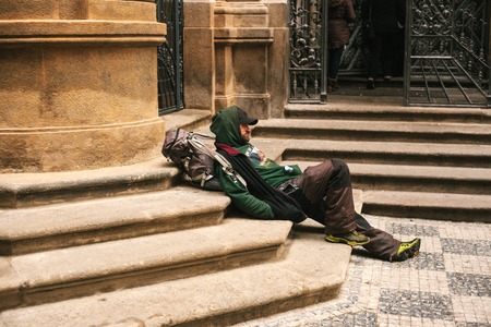 Prague, Czech Republic December 24, 2016 - Homeless hungry poor man sitting on the sidewalk in the city center. Unhappy man. Pragueのeditorial素材