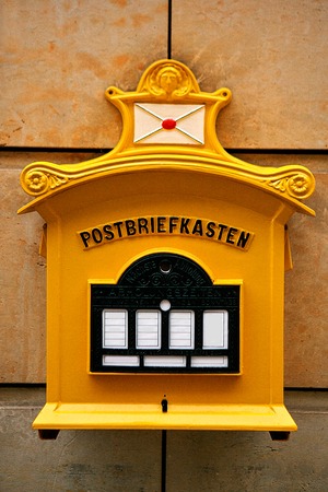 A traditional yellow letter box in Germany. Communication between people, sending letters and receiving messages.の写真素材
