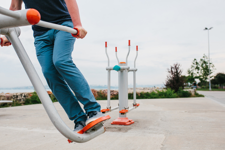 A man trains on sporting equipment in a city in the open air. The concept of a healthy lifestyle and accessibility of sports training for every person. Available sports equipment in a public place.の写真素材