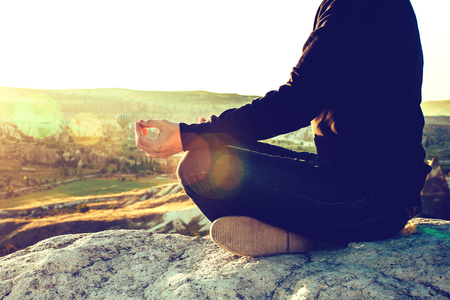 A man practices yoga at the top of the mountain at sunrise. Practices of relaxation.の写真素材