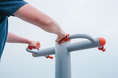 A man trains on sporting equipment in a city in the open air. The concept of a healthy lifestyle and accessibility of sports training for every person. Available sports equipment. Street sports.の写真素材
