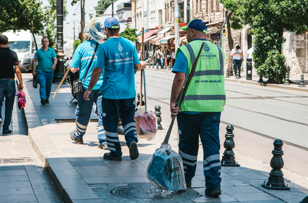 Istanbul, June 15, 2017: Three street janitors in uniforms are walking down the street holding brooms and dust pans.のeditorial素材