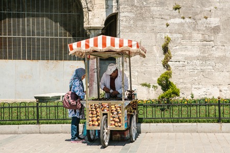 Istanbul, June 15, 2017: Pretty muslim woman in hijab purchasing roasted chestnuts from friendly street vendorのeditorial素材