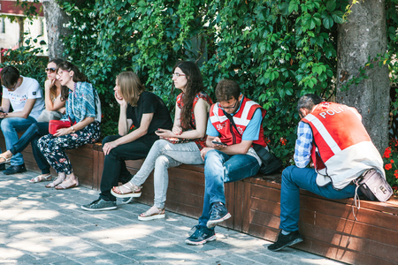 Istanbul, June 15 2017: two Turkish turism police officers at Sultanahmet square, with group of people sitting nearby.のeditorial素材
