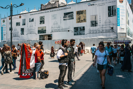 Istanbul, June 15 2017: People at Eminonu Square in the middle of the day - police officers, man with medical cast on his leg, casually dressed woman in white t-shirt and random passerby.のeditorial素材