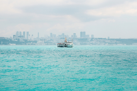 The ship sails along the blue water of the Bosphorus against the backdrop of a beautiful view of the European part of Istanbul. Scenic panoramic view. Travel, vacation.の写真素材