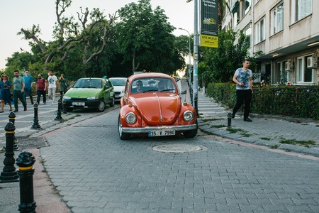 Istanbul, June 14, 2017: Red car with two men on the street in Moda neighborhood in Istanbul, Turkey