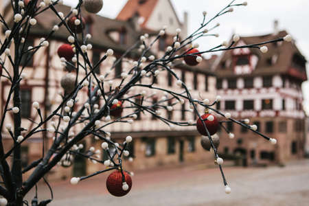 View of tree branch with Christmas lights and baubles, blurry building in the background. Selective...