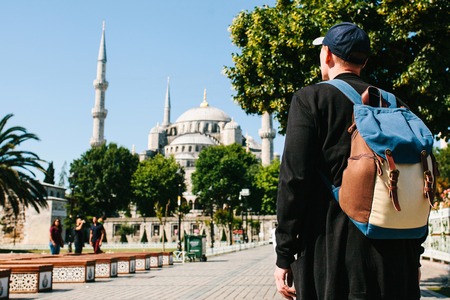 A man in a baseball cap with a backpack next to the blue mosque is a famous sight in Istanbul. Travel, tourism, sightseeing.の写真素材