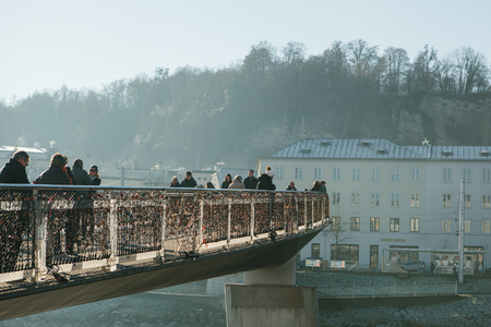 Austria, Salzburg, January 1, 2017: Mozarts pedestrian bridge connects the Old and New Towns. Pedestrians walk on the bridge. The hanging of locks on the bridge is a tradition.のeditorial素材