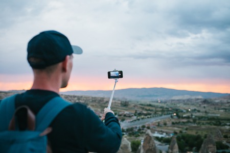 A tourist from a height looking at the sunset over the town of Goreme in Turkey makes a photo. Cappadocia. Tourism, rest, rest.の写真素材