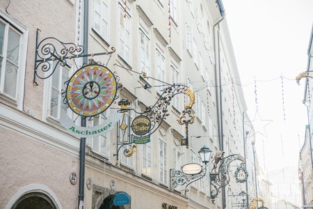 Austria, Salzburg, January 1, 2017: Advertising signs of shops on Getreidegasse street. A picturesque street in the old town. Salzburg Trade Center. Christmas holidays in Europe.のeditorial素材