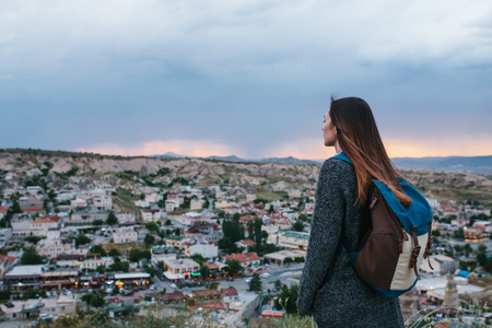Young woman tourist from a high point looking at the sunset over the town and dreaming. Tourism, rest, vacation.の写真素材