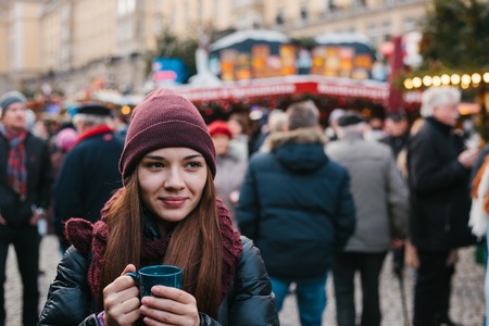 Beautiful young girl with a mug of hot drink at the Christmas market in Dresden. Celebrating Christmas in Europe. Holidays, vacations.の写真素材