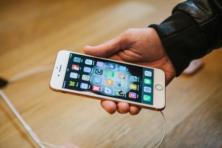 The day of the presentation of the iPhone 8 and iPhone 8 plus and the sale of new Apple products in the official Apple store in Berlin. The buyer holds the new iPhone 8 Plus in its hands and looks at its characteristics and mobile applications.のeditorial素材