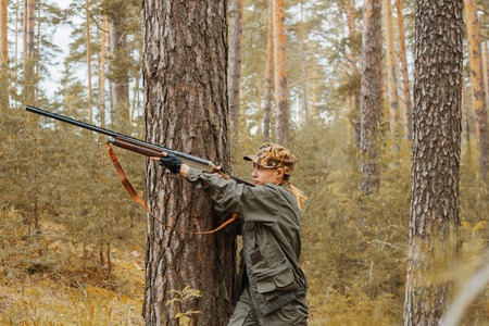 Woman hunter in the woods. Autumn hunting season. Outdoor sports.の写真素材