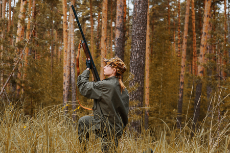 Woman hunter in the woods. Autumn hunting season. Outdoor sports.の写真素材