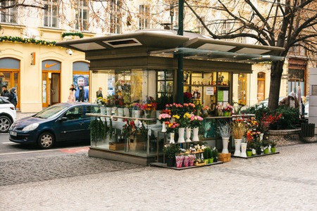 Prague street - flowers stall on the background of building decorated with Christmas garland and car standing along the roadのeditorial素材