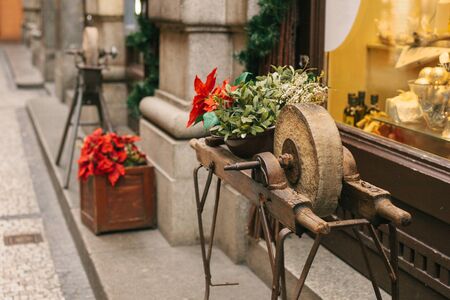 Ancient stone wheels on wooden structures decorated with red flowers at the entrance to the store...