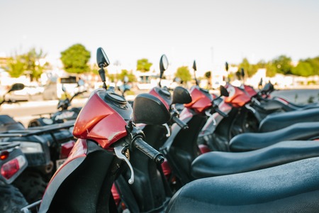 Lot of identical moto scooters stand in two lines on the street during sunny summer day.の写真素材