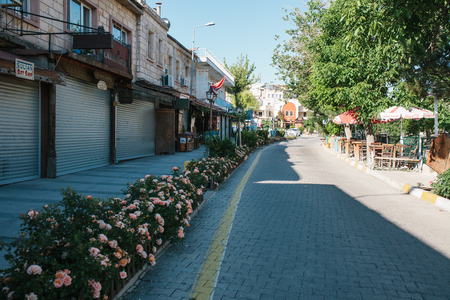 Turkey, Cappadocia, Goreme, June 12, 2017: Sunny morning in Goreme - street with flowers and closed shops and empty street cafesのeditorial素材