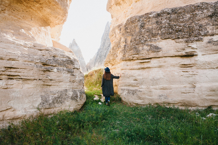 The woman stands between beautiful rocks and admires the landscape in Cappadocia in Turkeyの写真素材