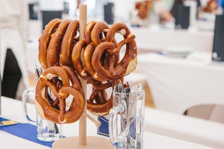 Celebration of the famous German beer festival Oktoberfest. Traditional pretzels called Brezel hang on the stand on the table. Waiting for visitors, cooked tables to celebrate the event.の写真素材