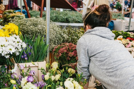 A small business for selling flowers. Street shop. A young girl is a salesman doing work. There are different kinds of flowers on the counter.の写真素材
