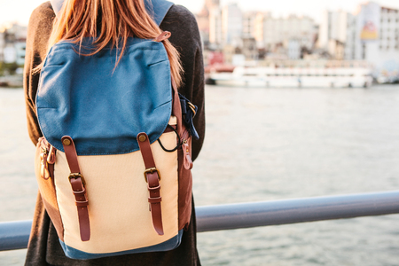 Young beautiful tourist girl with a backpack at sunset next to the Bosphorus on the background of Istanbul. Rest, vacation, hiking.の写真素材