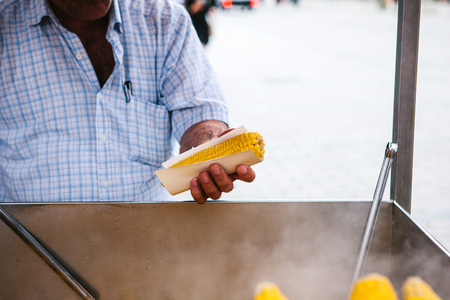 Small business. A man sells cooked corn to tourists and local residents in Istanbul, Turkeyの写真素材