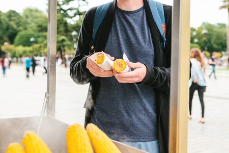 Small business. A man sells cooked corn to tourists and local residents in Istanbul, Turkey. The buyer takes foodの写真素材