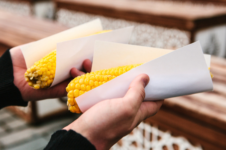 A man is holding in his hands delicious boiled corn bought from a seller in Sultanahmet Square in Istanbul, Turkeyの写真素材